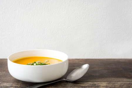 Pumpkin soup and pumpkin seeds on rustic wooden background