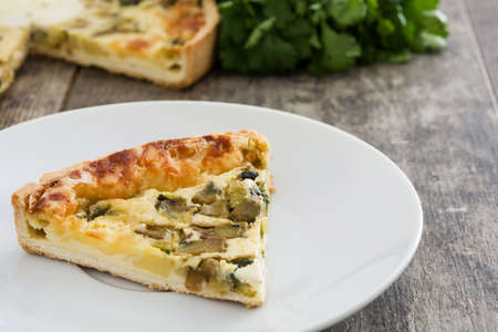 French quiche Lorraine with vegetables on a rustic wooden table