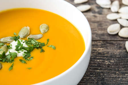 Pumpkin soup and pumpkin seeds on rustic wooden backgroundの写真素材