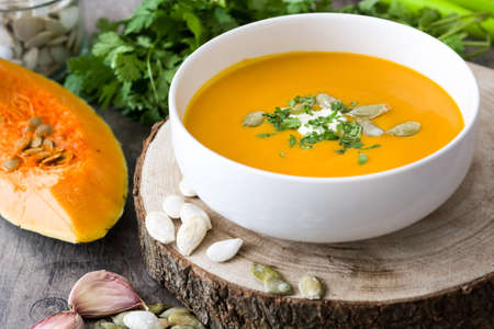 Pumpkin soup and ingredients on a rustic wooden tableの写真素材