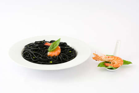 Black spaghetti with prawns and basil isolated on white backgroundの写真素材