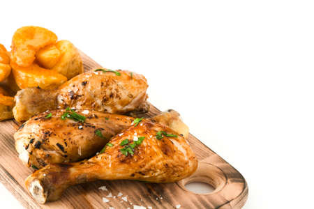 Roast chicken drumsticks on cutting board and chips isolated on white backgroundの写真素材