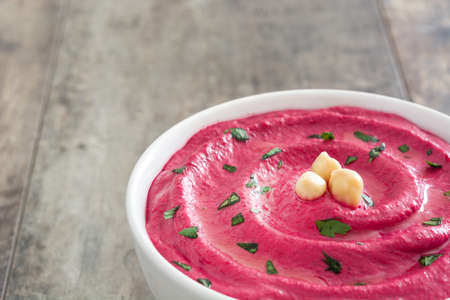 Beet hummus in a bowl on wooden tableの写真素材