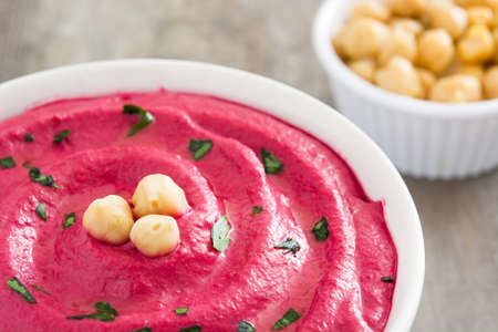 Beet hummus in a bowl on wooden tableの写真素材