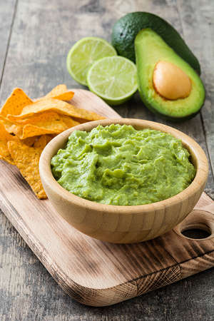 Nachos, guacamole and ingredients on wooden tableの写真素材