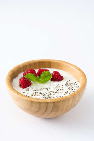 Chia yogurt with raspberries in a wooden bowl isolated on white background