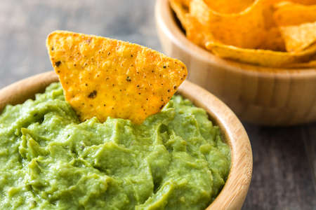 Guacamole in bowl with nachos on wooden tableの写真素材