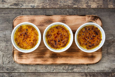 Traditional French creme brulee dessert with caramelized sugar on top, on wooden table