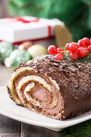 Christmas chocolate yule log cake with red currant on wooden background.copyspaceの写真素材