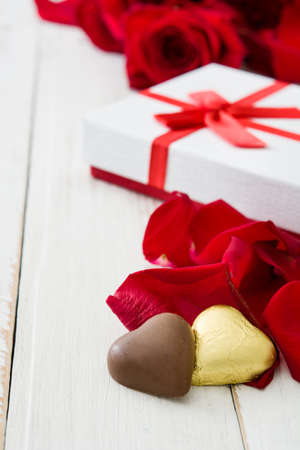 White gift box, roses and chocolate with heart shape on wooden table.copyspace