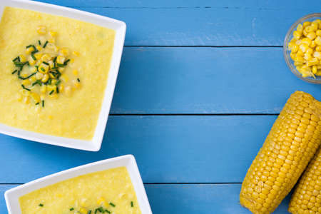 Corn soup in wooden bowl on blue backgroundの写真素材