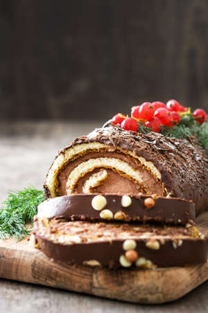 Christmas chocolate yule log cake with red currant on wooden background.copyspaceの写真素材