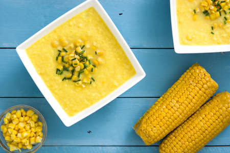 Corn soup in wooden bowl on blue backgroundの写真素材