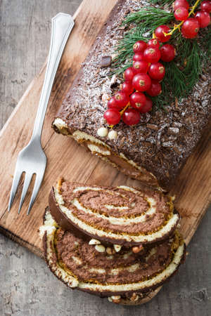 Christmas chocolate yule log cake with red currant on wooden background.top viewの写真素材