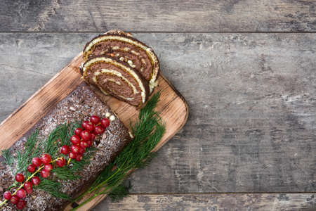 Christmas chocolate yule log cake with red currant on wooden background.copyspaceの写真素材