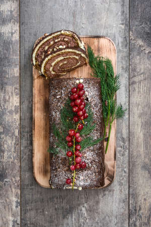 Christmas chocolate yule log cake with red currant on wooden background.copyspaceの写真素材