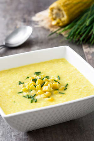 Corn soup in white bowl on wooden background