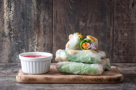 Vietnamese rolls with vegetables, rice noodles and prawns on wooden background