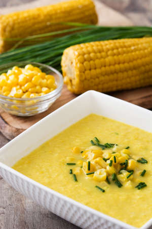 Corn soup in white bowl on wooden background
