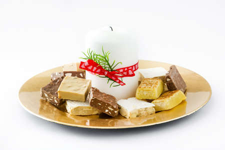 Christmas nougat and white candle on a golden plate isolatedの写真素材