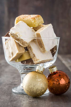 Variety of Christmas nougat in crystal glass and christmas ball on wooden background