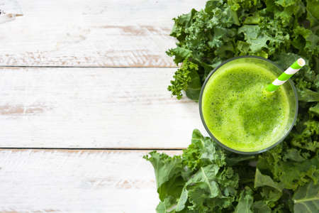 Kale smoothie in glass on white wooden background.Top viewの写真素材