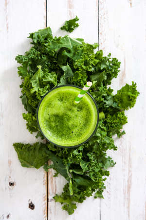Kale smoothie in glass on white wooden background.Top viewの写真素材