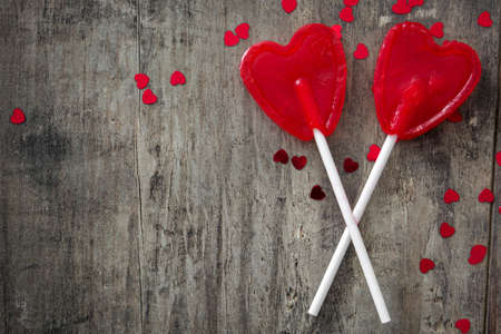 Red lollipops with heart shape on wooden background. Love concept. Valentine's Day.の写真素材