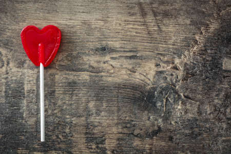 Red lollipop with heart shape on wooden background. Love concept. Valentine's Day.の写真素材