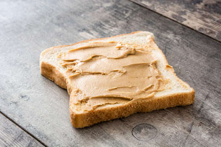 Peanut butter and toasts on wooden table.の写真素材