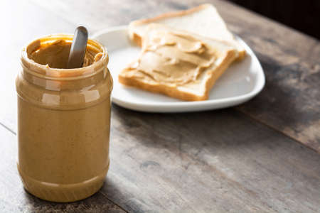 Peanut butter jar and toasts on wooden table. Copyspace.の写真素材