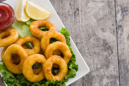 Fried calamari rings with lettuce and ketchup on wooden backgroundの写真素材