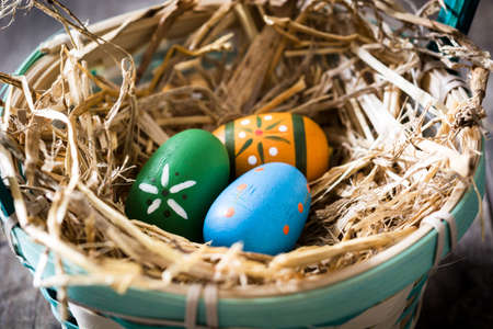 Colored easter eggs in a basket on wooden tableの写真素材
