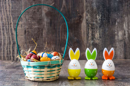 Easter rabbits and eggs in basket on wooden table