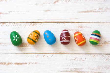Colored easter eggs on white wooden background.Top view
