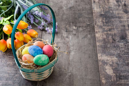 Easter eggs in a basket and tulips on wooden backgroundの写真素材