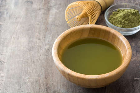 Matcha green tea in a bowl and bamboo whisk, on wooden backgroundの写真素材