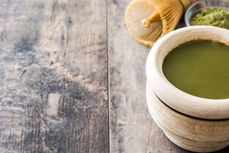 Matcha green tea in a bowl and bamboo whisk, on wooden backgroundの写真素材