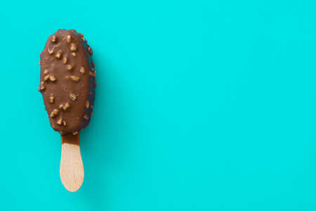 Black chocolate ice cream stick on blue background. Copy space