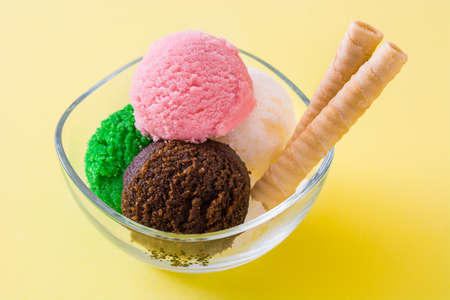 Ice cream scoops in crystal bowl on yellow background