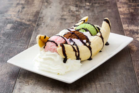 Banana split ice cream dessert with chocolate syrup on wooden backgroundの写真素材
