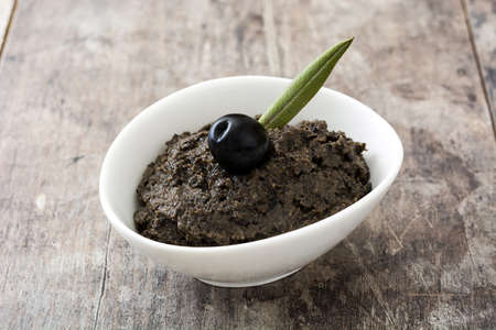 Black olive tapenade with anchovies, garlic and olive oil on wooden backgroundの写真素材