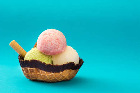 Ice cream scoops served in waffle basket on blue background. copyspaceの写真素材
