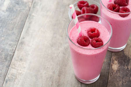 Raspberry smoothie in glass on wooden tableの写真素材