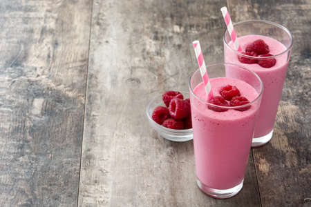Raspberry smoothie in glass on wooden tableの写真素材