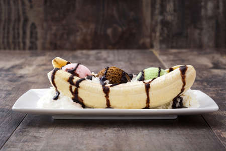 Banana split ice cream dessert with chocolate syrup on wooden backgroundの写真素材