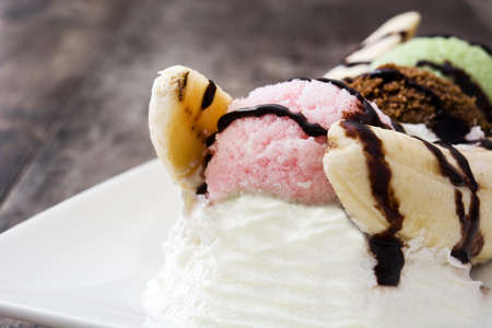 Banana split ice cream dessert with chocolate syrup on wooden backgroundの写真素材