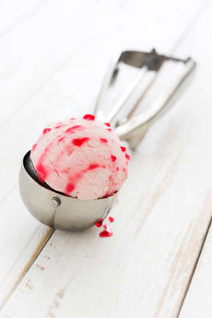 Strawberry ice cream scoop on white wooden tableの写真素材