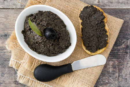 Black olive tapenade with anchovies, garlic and olive oil on wooden table