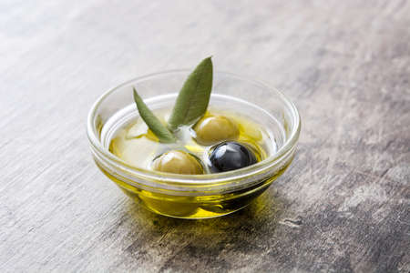 Virgin olive oil in a crystal bowl on wooden backgroundの写真素材